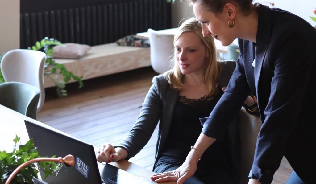 two woman collaborating on a laptop